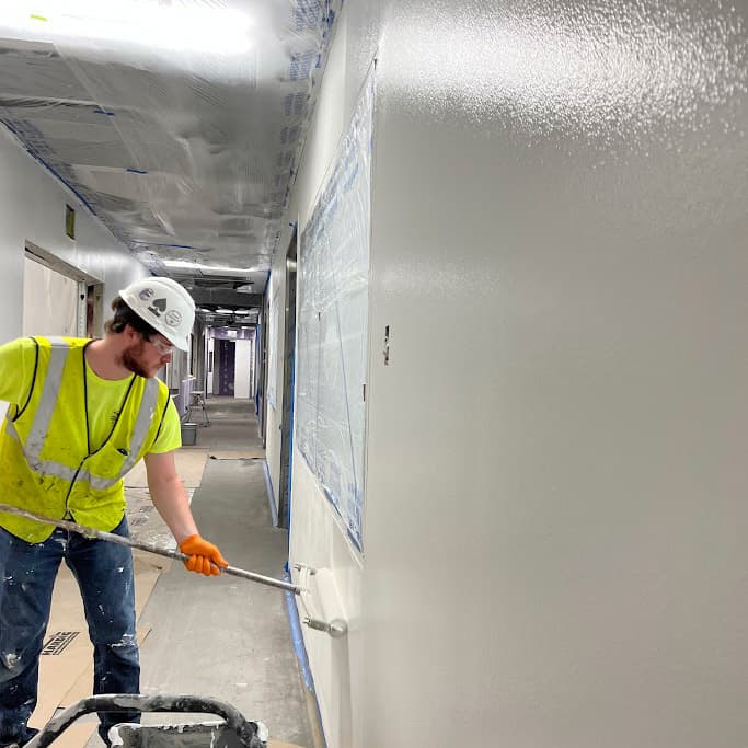an image of a worker painting the wall with a roller brush